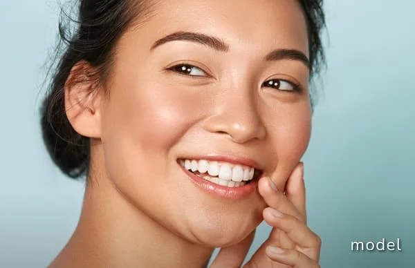 Chemical Peels model image of woman touching face smiling looking away from camera