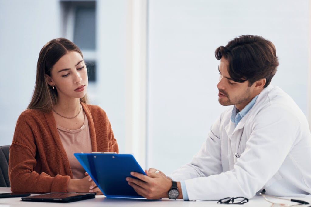 Woman looking at a plastic surgeon's before and after photos at a rhinoplasty consultation