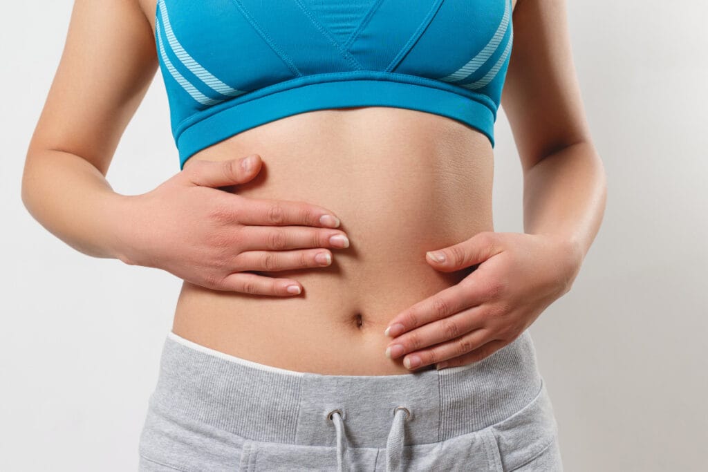 Faceless woman in athletic gear putting hands around belly button